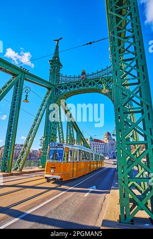 Die klassische gelbe Straßenbahn fährt auf der Liberty Bridge in Budapest, Ungarn Stockfoto