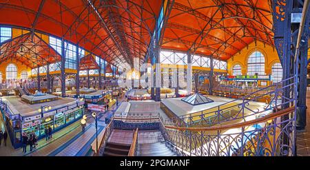 BUDAPEST, UNGARN - 22. FEBRUAR 2022: Panoramablick auf das Innere der zentralen Markthalle mit dekorativen Grills, Metallsäulen, Pavillons mit Verkaufsständen und Geschäften Stockfoto