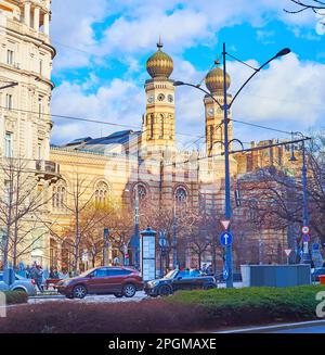 Die Straßenszene mit Verkehrsstau und die historische Synagoge der Dohany Street mit Uhrtürmen und bulbusförmigen Kuppeln, Belvaros, Budapest, Ungarn Stockfoto