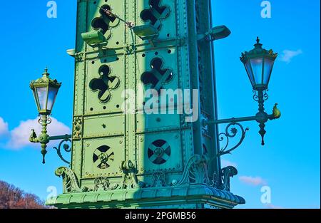 Die malerischen alten Lampen auf der Stützsäule der Freiheitsbrücke mit Kabelhalterungen, die mit Nieten, Schnitzereien und geschmiedeten Elementen in Budapest, Ungarn, dekoriert sind Stockfoto