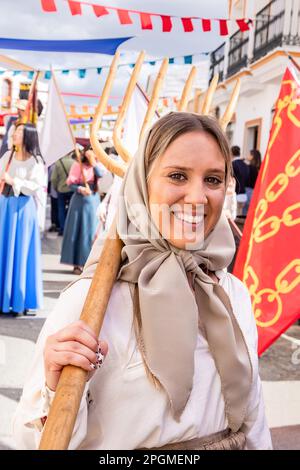 Huelva, Spanien - 18. März 2023: Wunderschöne junge Frau, die als Landwirtin verkleidet ist, mit antiken Kostümen und einer Heugabel in der Parade der mittelalterlichen Entdeckungen Stockfoto