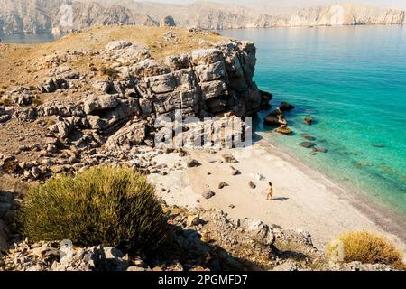 Aus der Vogelperspektive isolierte Touristenfrau im Bikini Spaziergang am weißen Sandstrand allein auf der persischen Golf Mirellas Insel. Musandam. Oman Stockfoto