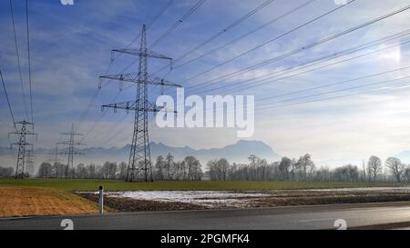 Landschaft im Winter hinter der Straße mit vielen Power-Pylons im Hintergrund Stockfoto