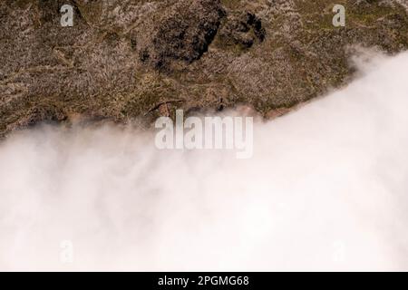 Drohnenfotografie von Berggipfeln und gestoppten Wolken durch die Bergkette an sonnigen Sommertagen. Direkt darüber Stockfoto