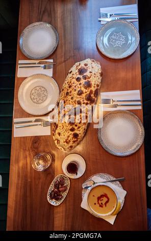 Hamburg, Deutschland. 23. März 2023. Ein Glas Wasser, ein Glas Tee, eine Schüssel Datteln, Suppe und Steinbrot von Sisme Ekmek liegen im Restaurant Pamukkale Köz auf dem Tisch. Der muslimische Fastenmonat Ramadan beginnt in diesem Jahr am 23. März und endet am 20. April. Kredit: Georg Wendt/dpa/Alamy Live News Stockfoto