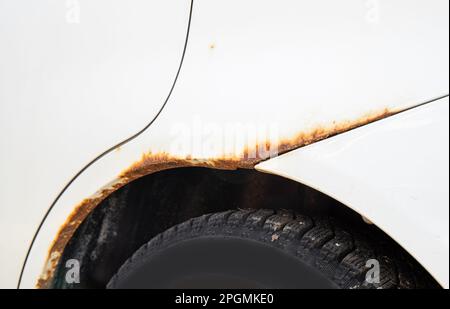 Nahaufnahme der weißen Fahrzeuglackierung mit Rost am Fahrzeug. Neues, modernes Auto mit Rostproblem. Stockfoto