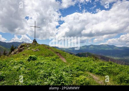 Religiöses Kreuz am Straßenrand mit orthodoxer Heiliger Ikone auf einem Hügel auf der M-20 Straße zum Tskhratskaro Pass mit der grünen Bergkette Trialeti (Kaukasus). Stockfoto