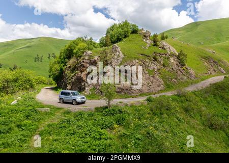 Fahrt im Geländewagen auf der M-20, gewundene Schotterstraße in Richtung Tskhratskaro Pass, Georgia mit Trialeti (Kaukasus)-Bergen und grünem Grasland. Stockfoto