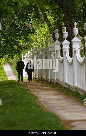 Ein Paar, das an einem dekorativen Zaun vorbei an der alten First Congregational Church in Bennington Vermont spaziert Stockfoto