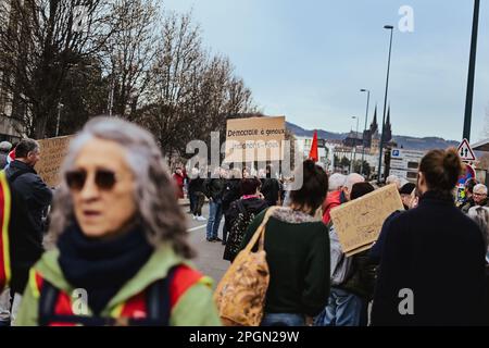 23. März 2023, Clermont Ferrand, Auvergne Rhone Alpes, Frankreich: Im Hintergrund hält eine Person ein Schild mit der Aufschrift Demokratie auf den Knien, lassen Sie uns empört sein! Frankreich streikt erneut gegen die zutiefst unpopuläre Rentenreform, die Ministerpräsident Elisabeth letzte Woche unter Verwendung von Artikel 49,3 durch das Parlament gedrängt hat. Am Mittwoch kündigte Präsident Macron im Fernsehen an, dass er sich dafür aussprach, dass die Renten noch vor Jahresende umgesetzt werden. (Kreditbild: © Adrien Fillon/ZUMA Press Wire) NUR REDAKTIONELLE VERWENDUNG! Nicht für den kommerziellen GEBRAUCH! Stockfoto