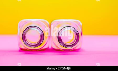 Zwei leere Flaschen auf farbenfrohem pinkfarbenen und gelben Hintergrund Stockfoto