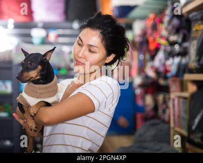 Porträt einer lächelnden Frau mit seinem Hund in Winterkleidung, die den Heimtierbedarf besucht Stockfoto