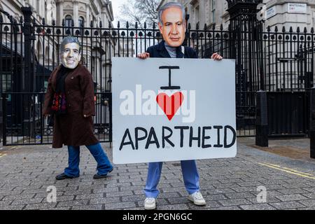 London, Großbritannien. 23. März 2023. Aktivisten von Amnesty International UK mit Masken inszenieren vor der Downing Street am Vorabend eines Besuchs des israelischen Premierministers Benjamin Netanjahu einen Protest gegen die „israelische Apartheid“. Amnesty International veröffentlichte 2022 einen großen Bericht, in dem behauptet wird, dass Israels Behandlung der Palästinenser dem internationalen Verbrechen der Apartheid gleichkommt, und Amnesty International UK hat vor Benjamin Netanjahus Besuch an Premierminister Rishi Sunak geschrieben, in dem es Bedenken hinsichtlich des Engagements des Vereinigten Königreichs für die internationale Justiz im Lichte dessen geäußert hat Die stillschweigende Akzeptanz des Okku Israels Stockfoto