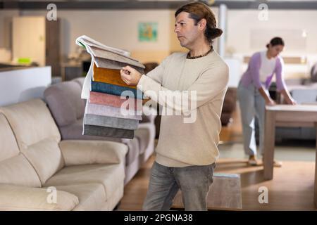 Ein Mann mittleren Alters wählt die Polsterfarbe der Möbel Stockfoto