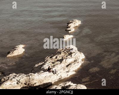 Ein Paar sitzt zusammen auf Rocks, Pendennis Point, Falmouth, Cornwall, England, UK. GB. Stockfoto