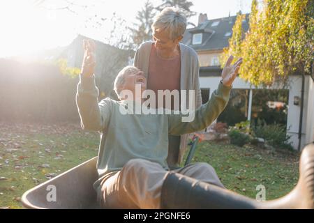 Gerne älteres Paar das Spaß mit Schubkarre im Garten Stockfoto