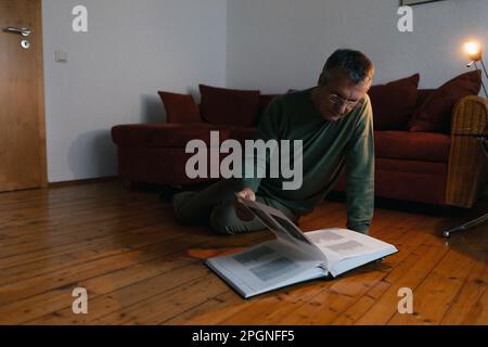 Ältere Menschen auf dem Boden zu Hause sitzen auf Fotoalbum Stockfoto