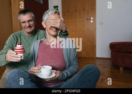 Gerne älteres Paar auf dem Boden sitzend zu Hause Spaß Stockfoto