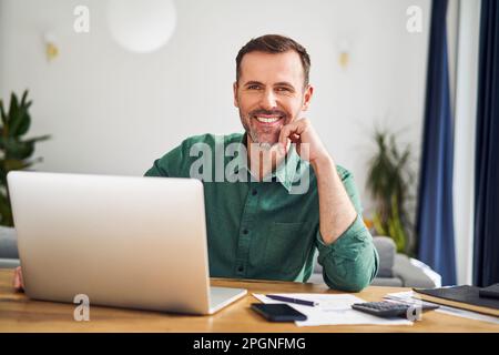 Mann sitzt am Schreibtisch mit Laptop, der von zu Hause aus arbeitet Stockfoto