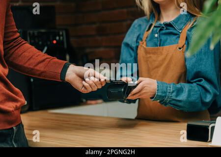 Hand eines Gastes, der im Café per Kreditkarte bezahlt Stockfoto