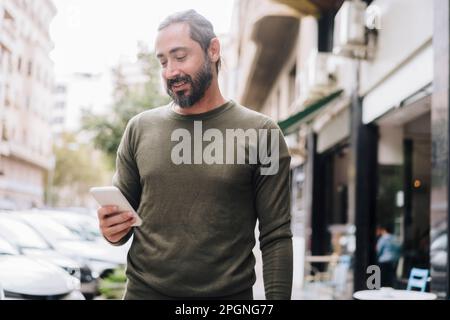 Lächelnder bärtiger Mann mit Smartphone Stockfoto
