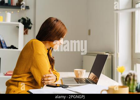 Glückliche Freiberuflerin, die per Laptop per Videoanruf telefoniert Stockfoto