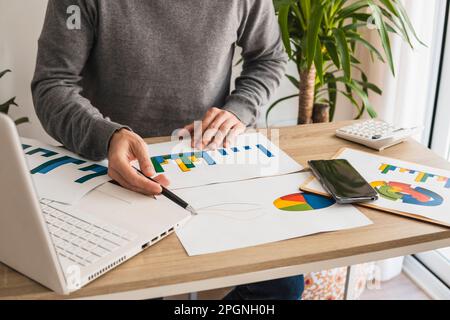 Geschäftsmann mit Diagrammen und Tortendiagrammen, der im Büro arbeitet Stockfoto