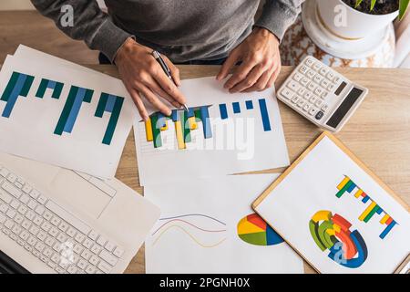 Hände eines Geschäftsmannes, der Diagramme und Diagramme am Schreibtisch im Büro analysiert Stockfoto