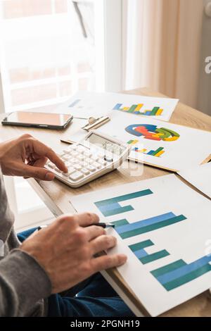 Hände eines Geschäftsmannes, der im Büro Diagramme prüft und Berechnungen macht Stockfoto