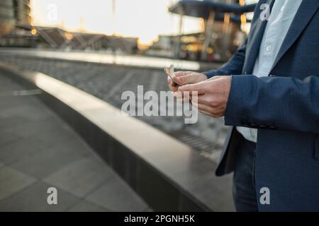 Hände eines reifen Geschäftsmanns mit Geld im Büropark Stockfoto