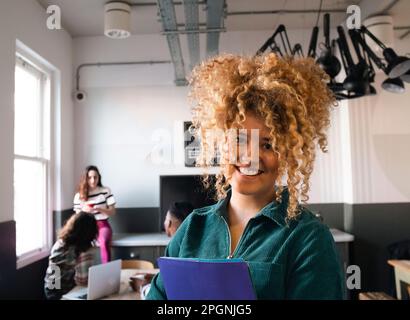 Glückliche Geschäftsfrau mit lockigen Haaren im Büro Stockfoto