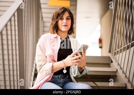 Frau mit Smartphone, die auf der Treppe sitzt Stockfoto
