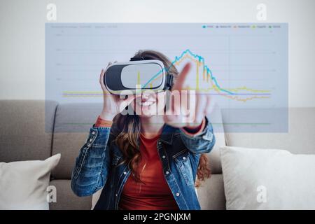 Glückliche Frau, die zu Hause einen Virtual-Reality-Simulator trägt Stockfoto