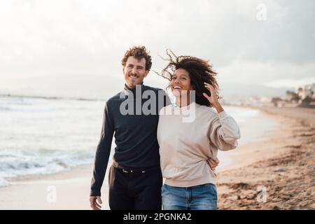 Glücklicher Mann und glückliche Frau, die zusammen am Strand spazieren gehen Stockfoto