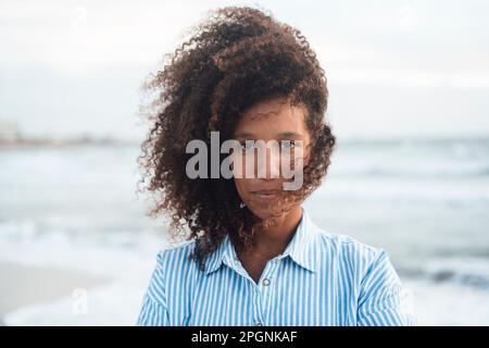 Eine Frau mit lockigem Haar vor dem Meer Stockfoto
