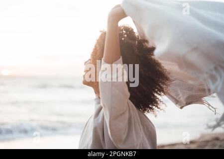 Glückliche junge Frau mit Schal am Strand Stockfoto