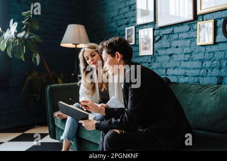 Produzent und Schauspielerin diskutieren zusammen, sitzen auf dem Sofa am Filmset Stockfoto
