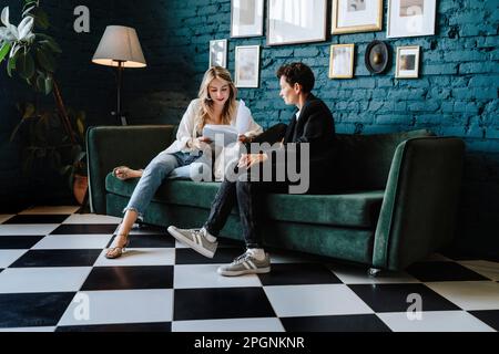 Schauspielerin, die Drehbuch liest, sitzt mit dem Produzenten auf dem Sofa am Filmset Stockfoto