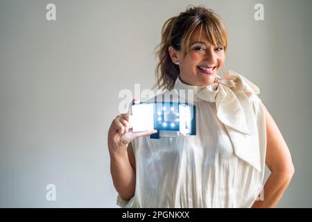 Glückliche Frau, die Vergrößerungsgeräte vor weißem Hintergrund zeigt