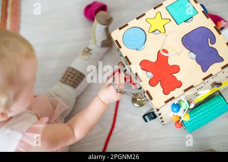 Gaming-Board. Das Kind nimmt die Figur in den hölzernen Sortier- und Stapelspielzeugen für das Baby mit. Hölzerner Montessori-Spielwürfel mit interessanten pädagogischen Aktivitäten Stockfoto