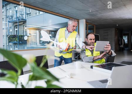 Älterer Ingenieur mit Windturbinenrotor, der den Kollegen im Büro erklärt Stockfoto