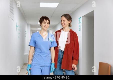 Lächelnder Patient steht mit Arzt im Flur des Krankenhauses Stockfoto
