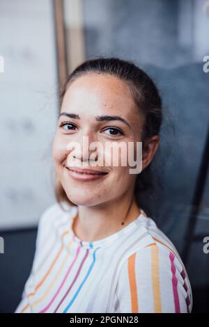 Lächelnde Geschäftsfrau im Büro sitzen Stockfoto