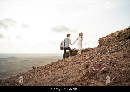 Ein junges Paar, das Händchen hält und auf den Bergen wandert Stockfoto