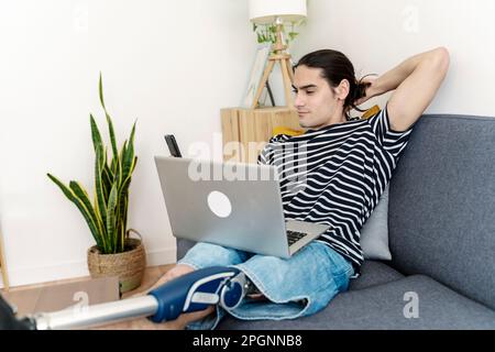 Junger Mann mit amputiertem Bein, der zu Hause ein Smartphone auf dem Sofa benutzt Stockfoto