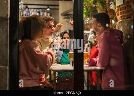 Junge Freunde mit Drinks, die Spaß im Restaurant haben Stockfoto