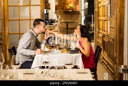 Ein junger Mann küsst die Hand seiner Freundin im Restaurant Stockfoto