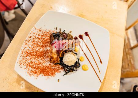 Gegrillter Oktopus mit Safran- und Sepia-Pasta auf Teller im Restaurant Stockfoto