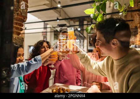 Glückliche Freunde, die Biergläser im Restaurant toasten Stockfoto