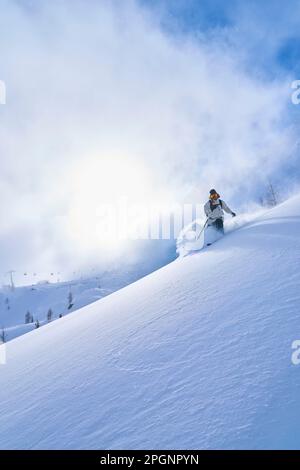 Eine Frau, die auf einem schneebedeckten Berg Ski fährt Stockfoto